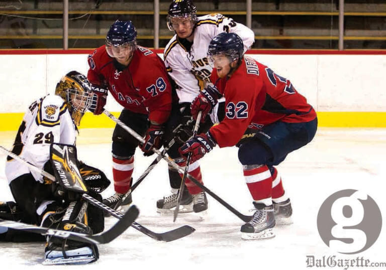 Acadia’s Jacob Dietrich tries to jam the puck under Tigers goalie Bobby Nadeau. Photo by Martina Marien