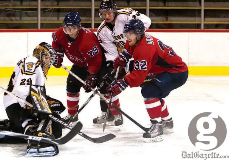 Acadia’s Jacob Dietrich tries to jam the puck under Tigers goalie Bobby Nadeau. Photo by Martina Marien