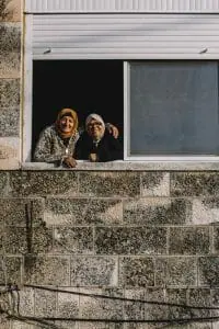 Two women enjoy the comfortable December weather in the window of a home. At-Tur, East Jerusalem.