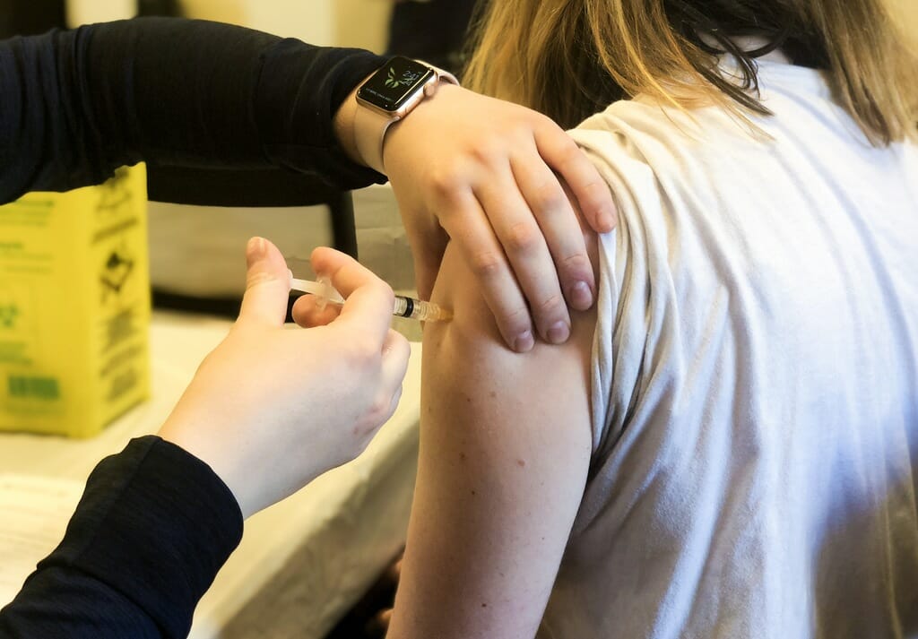 A person giving a flu shot to a patient.