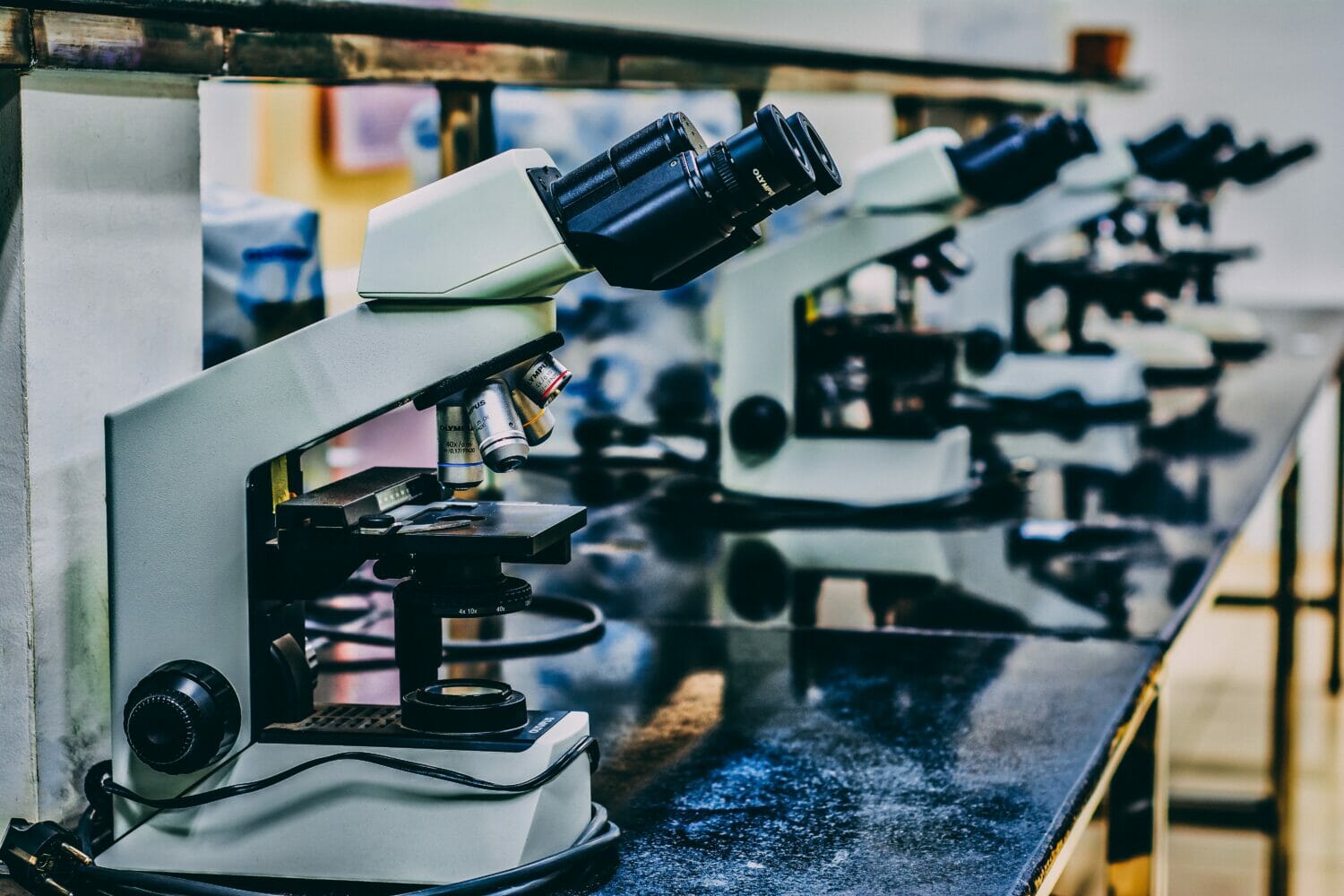 In this image: a line of microscopes on a black table