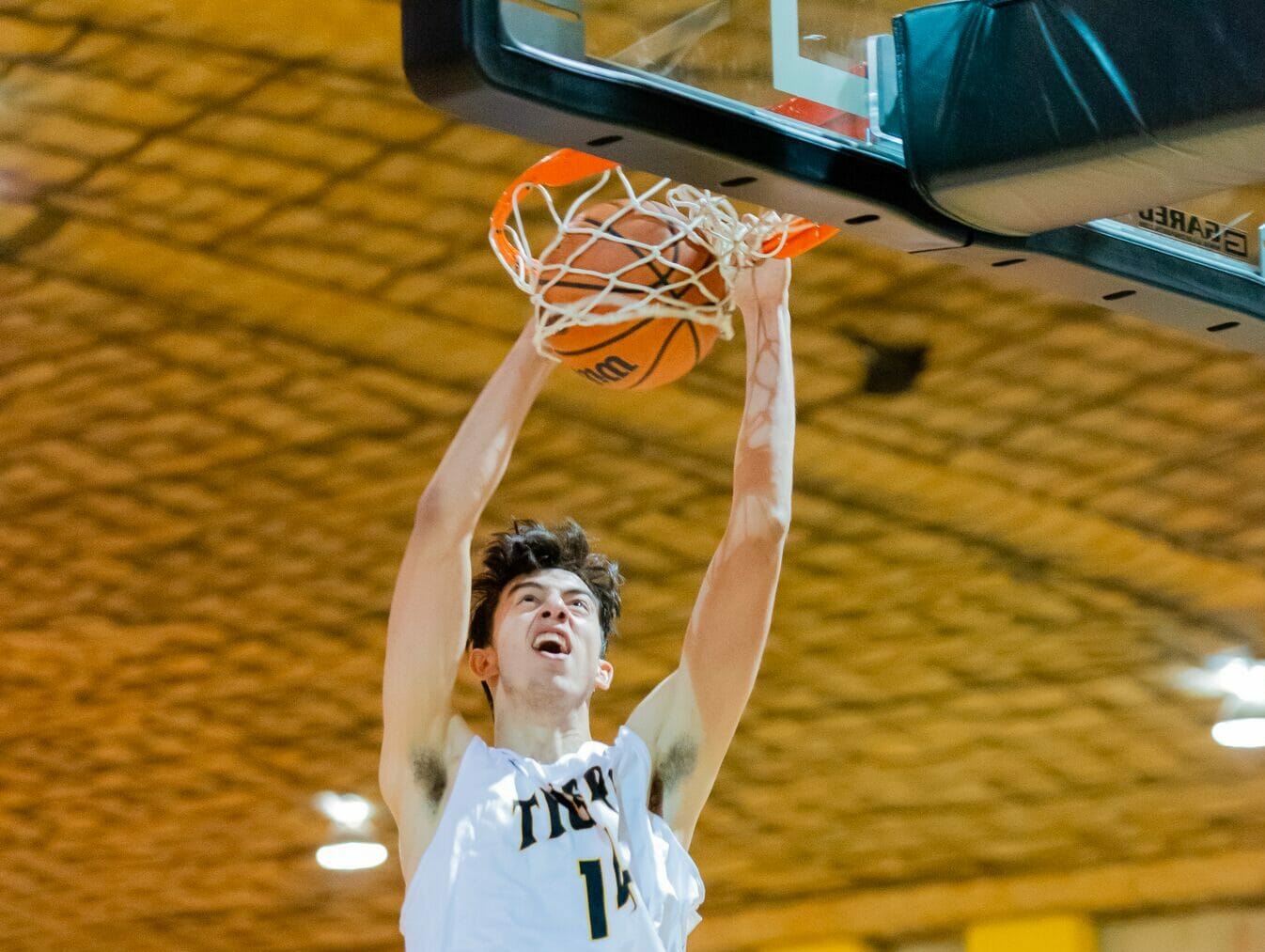 In this image: Sascha Kappos slam dunks the ball into the basketball hoop.