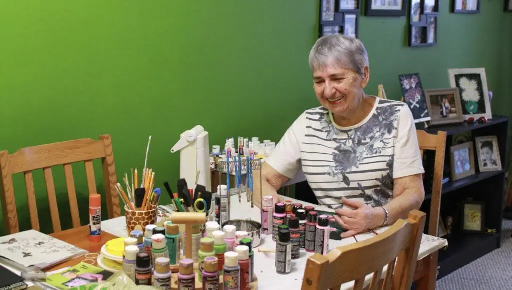 In this image: Dorothea McCorriston in front of her paint supplies.