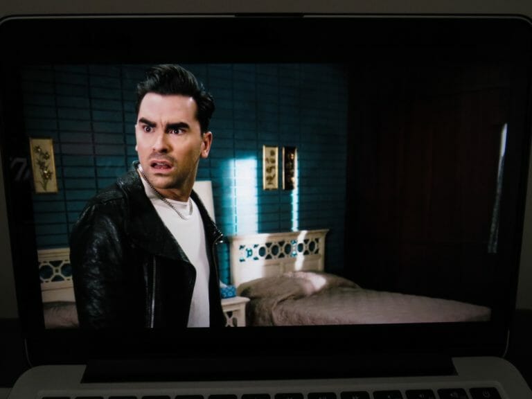 In this image: Dan Levy on-screen in a still shot of Schitt's Creek playing on a laptop.