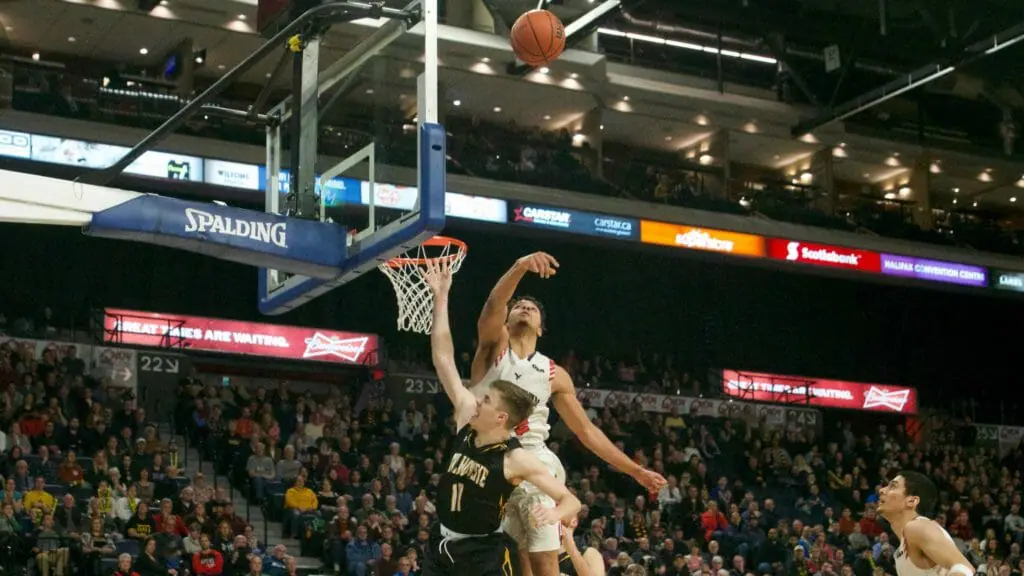 In this image: Keevan Veinot's shot is blocked by Eddie Ekiyor.