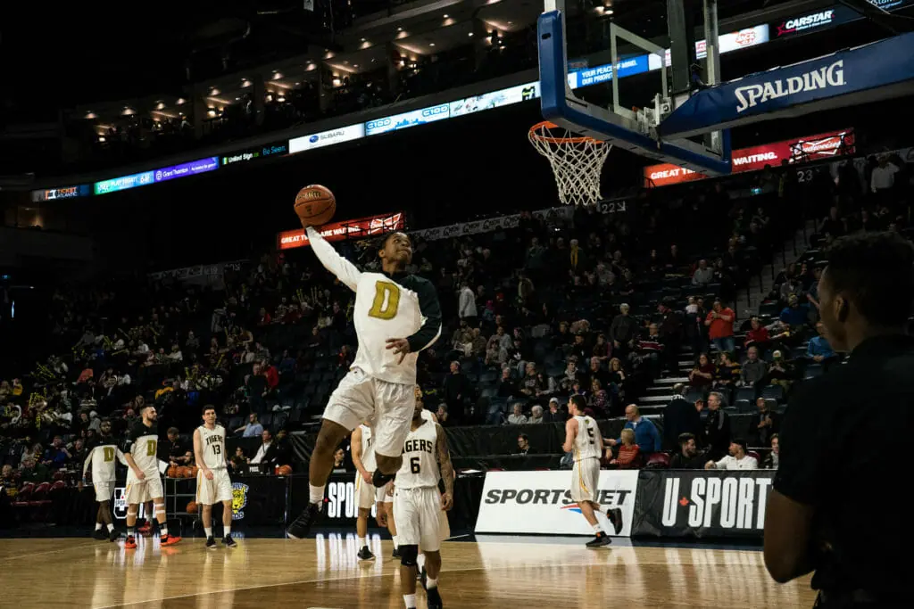 In this image: A Dalhousie player goes to dunk the basketball.
