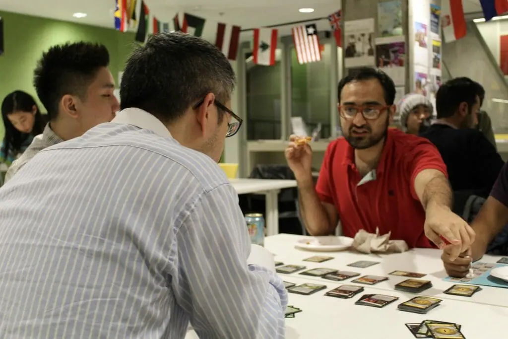 In this image: A man points to something while playing a card game.