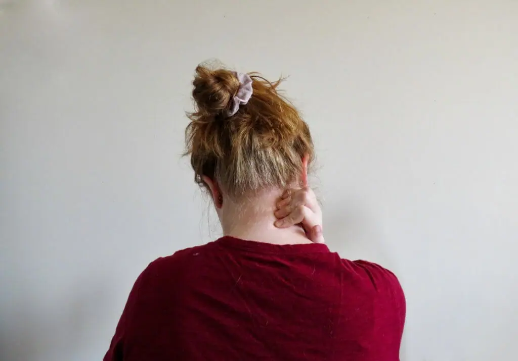 In this image: back of woman rubbing her neck