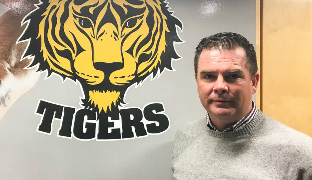 In this image: Tim Maloney beside a Dal Tigers logo.