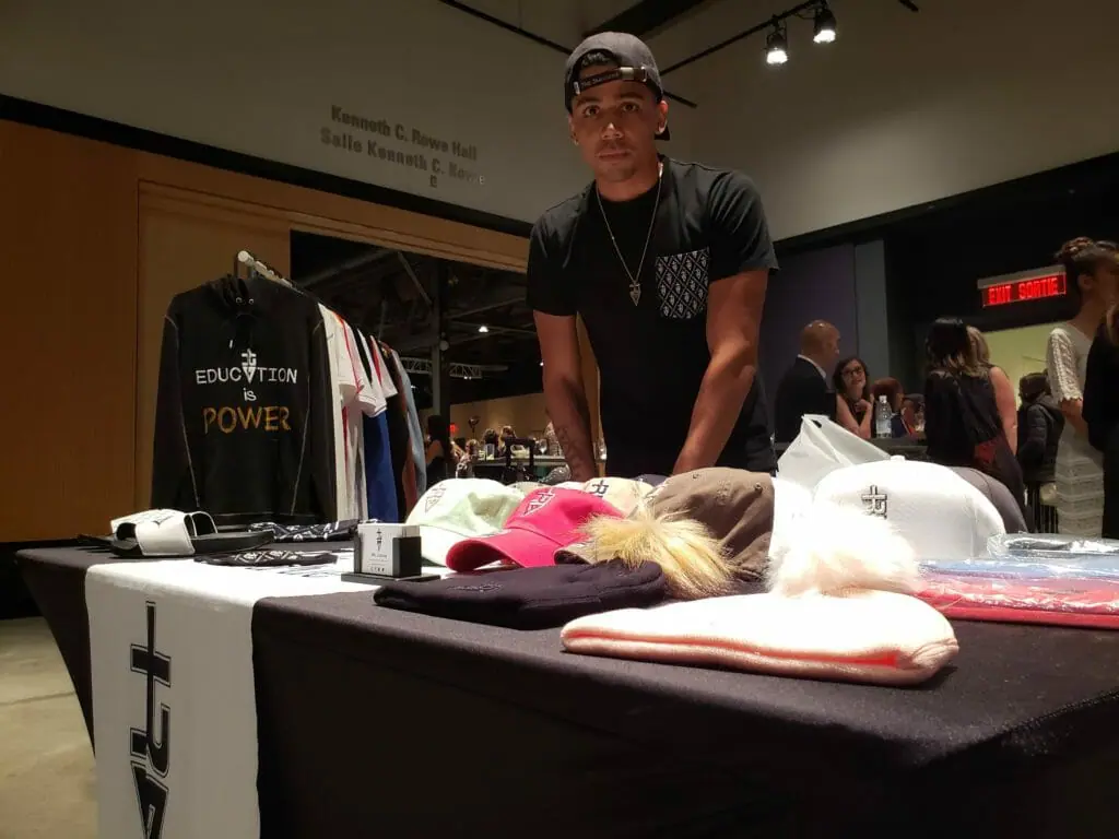 In this image: A man stands behind a desk selling merchandise.
