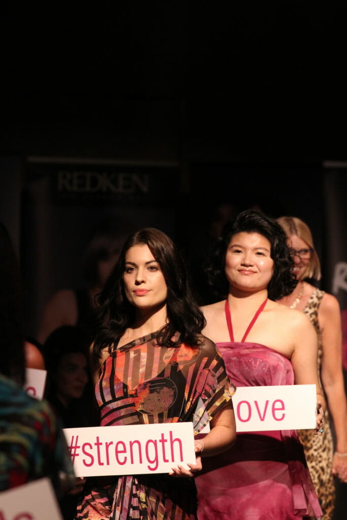 In this image: models hold signs on the runway with one saying #strength.