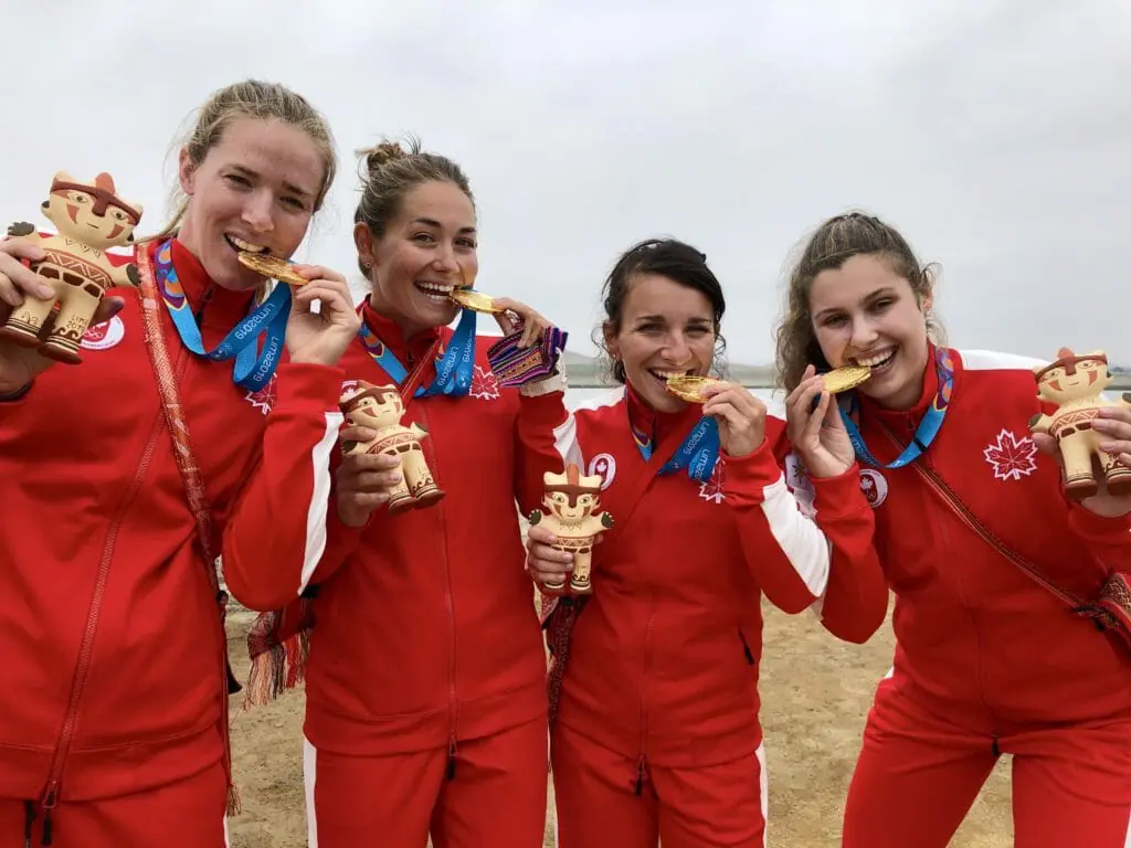 In this image: The four athletes who won the gold medal in the 500 metre kayak sprint pose while biting their medals.