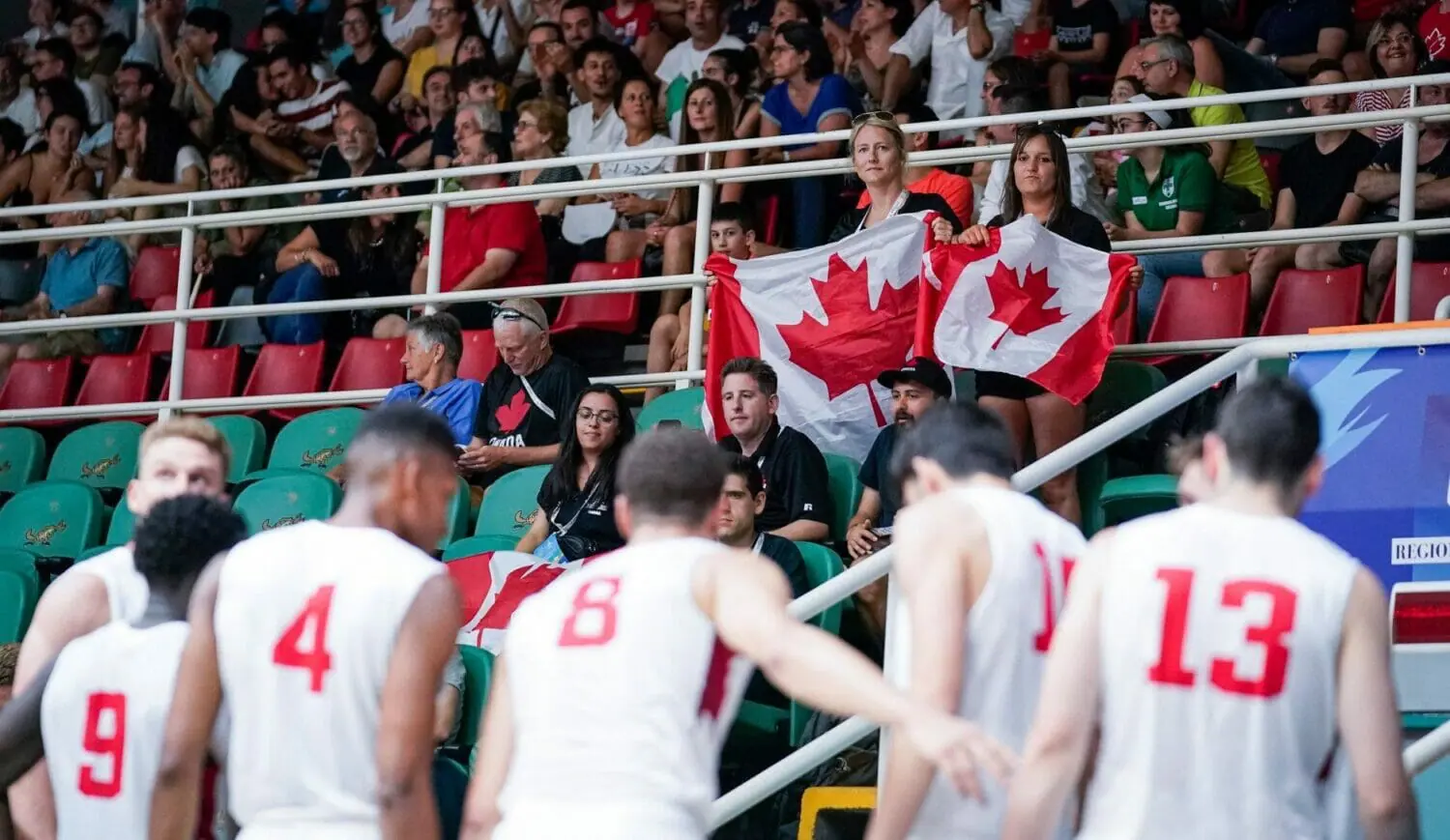 In this image: Two members from the crowd hold Canada flags.