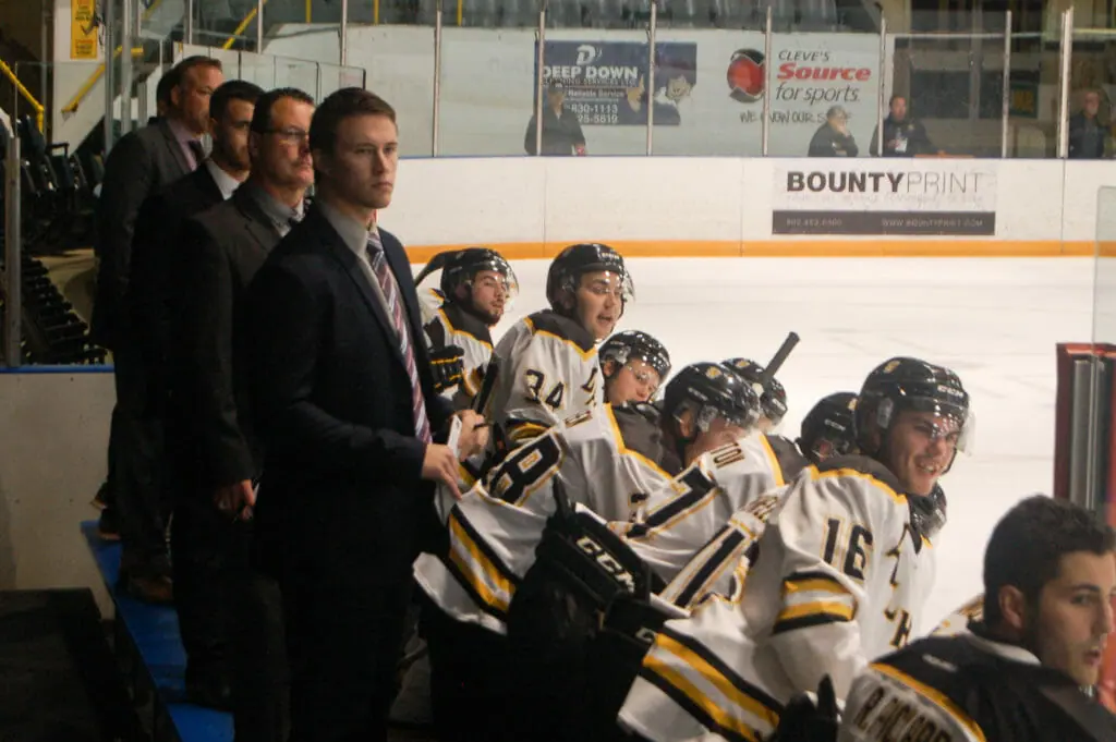 In this image: The Tiger's men's hockey team coaches and players at a game.
