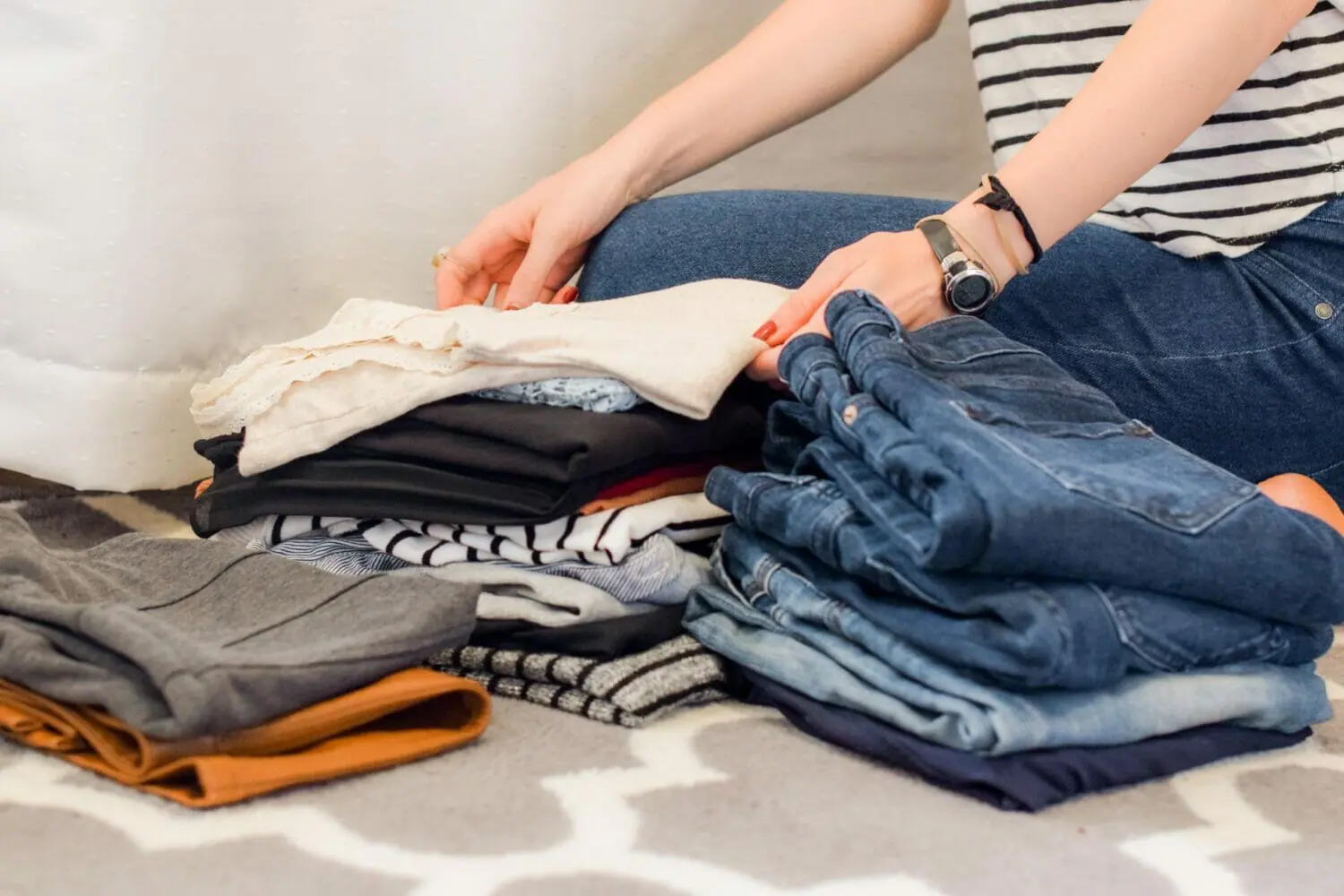 In this image: A person folds a pile of clothes.