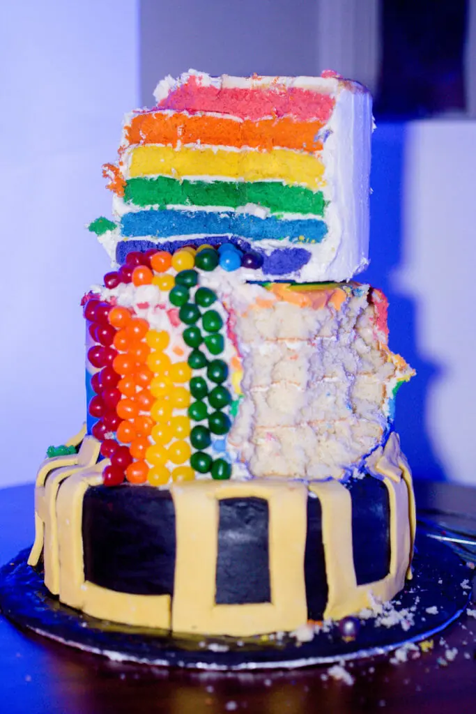 In this image: A white cake decorated with the pride flag colours.
