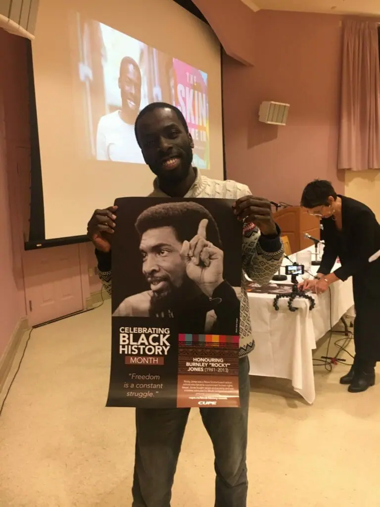 In this image: Desmond Cole holds a Black History Month poster.