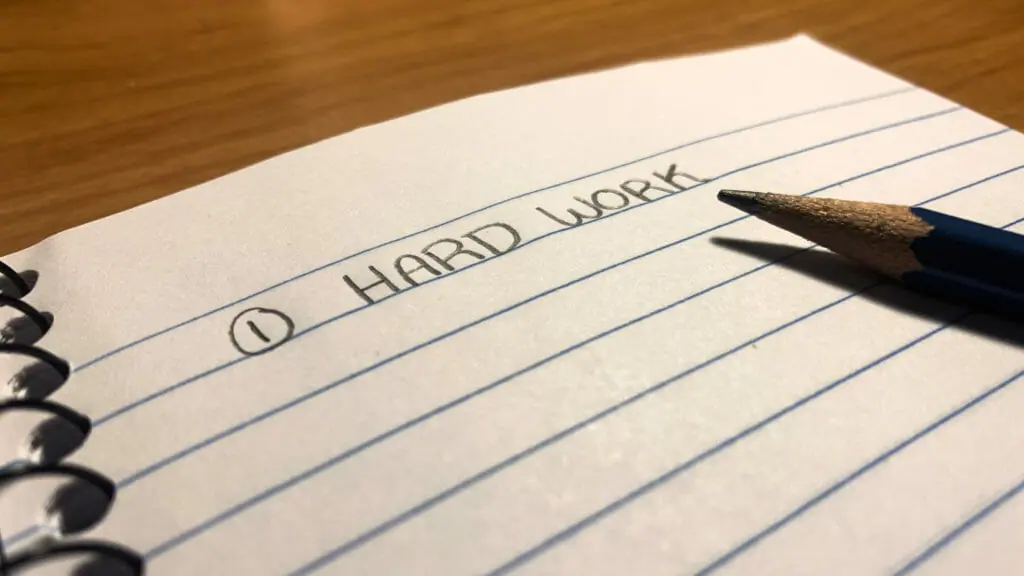 In this image: A notebook with "Hard Work" written on it.