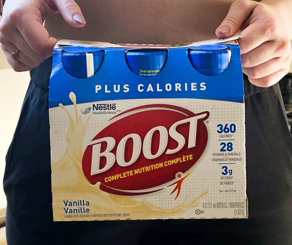 In this image: A person holds a package of Boost.