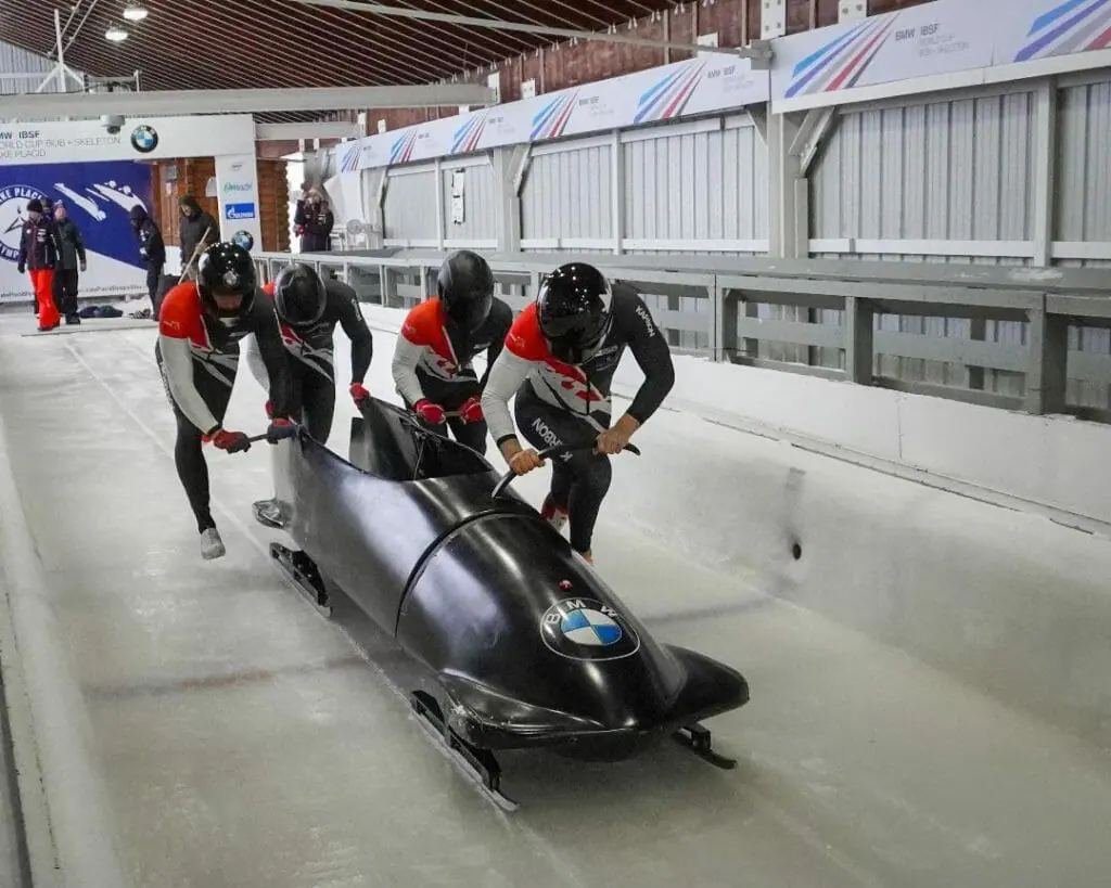 In this image: A bobsled teams pushes off at the start of a track.