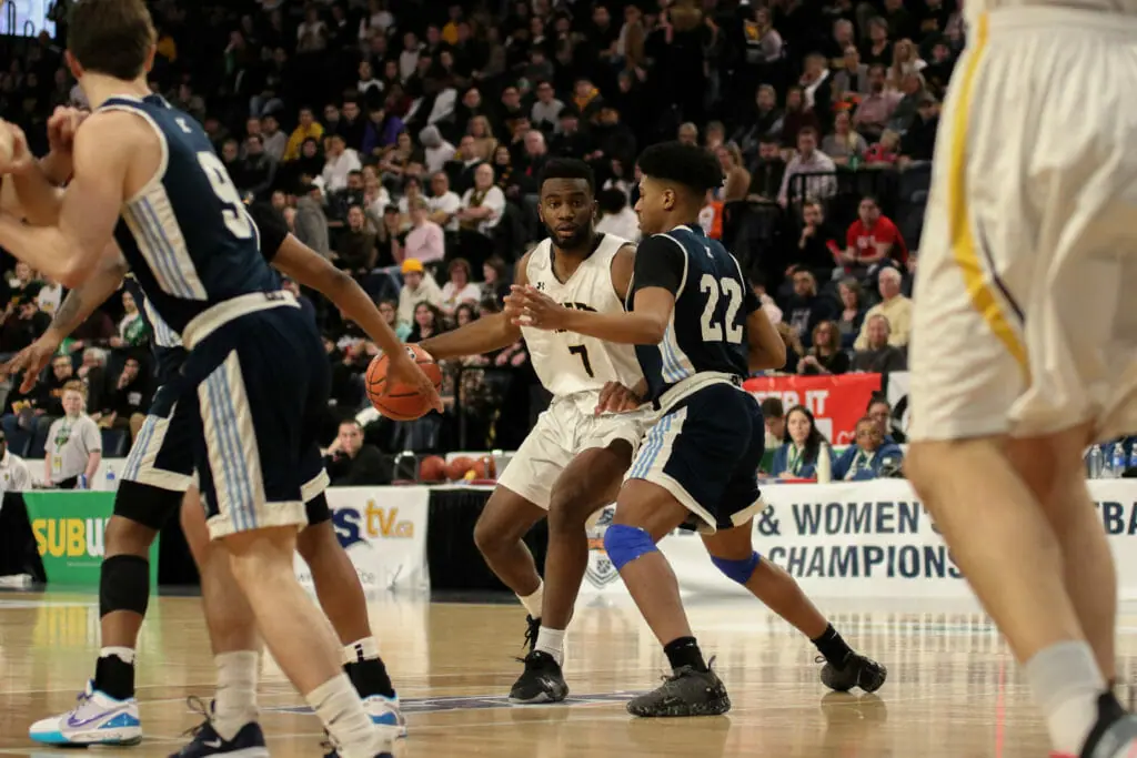In this image: Jordan Wilson (left) dribbles the basketball.