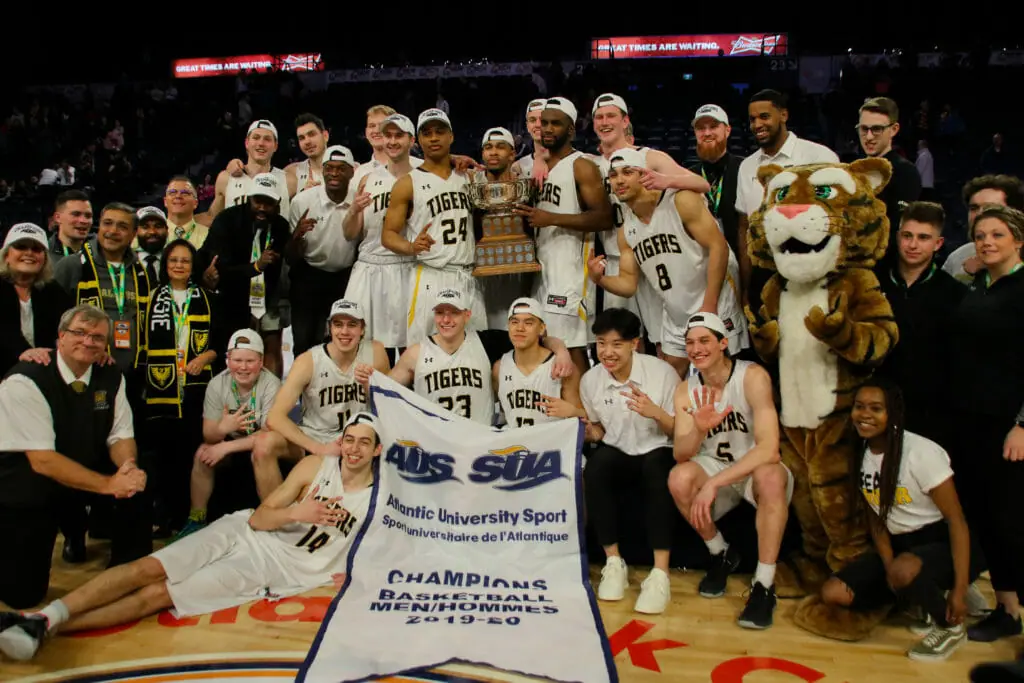 In this image: The Dalhousie men's basketball team and others posing with the AUS champions banner.