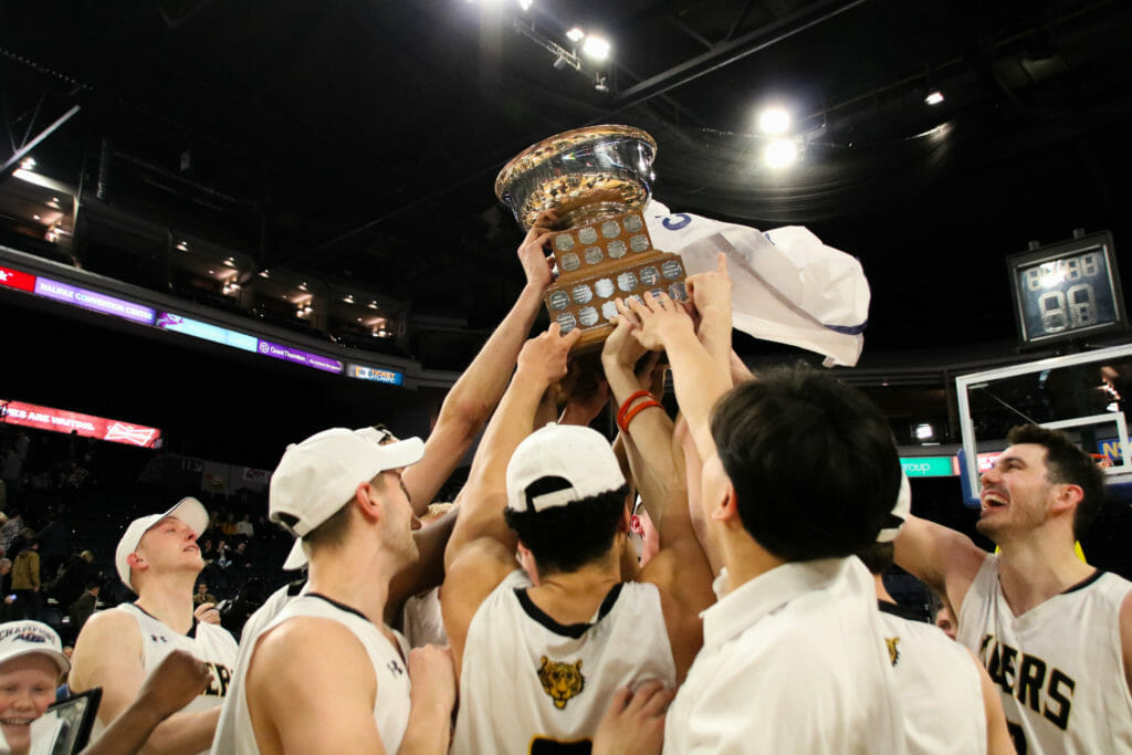 In this image: Multiple Tigers hold up the AUS championship trophy.