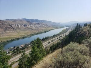 In this image: Looking over a highway, small community and river.