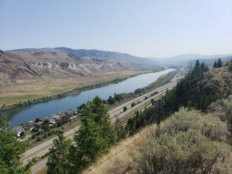 In this image: Looking over a highway, small community and river.