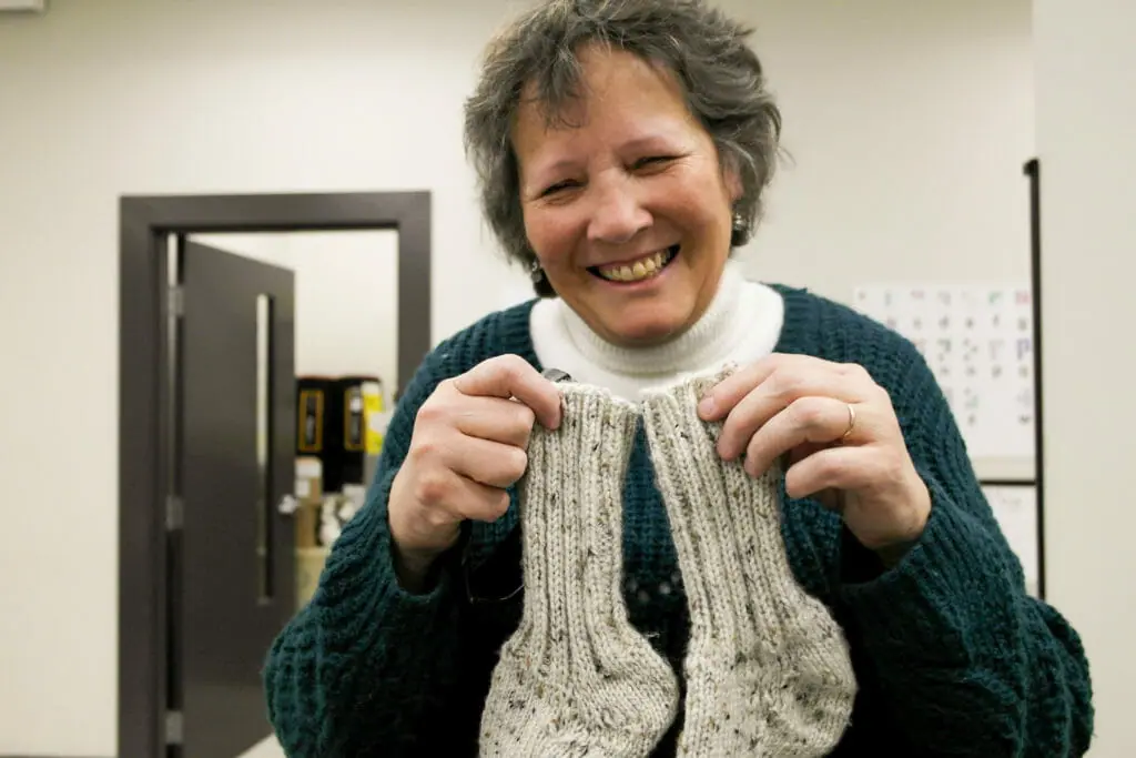 In this image: Irene Swain holds a pair of knitted socks.
