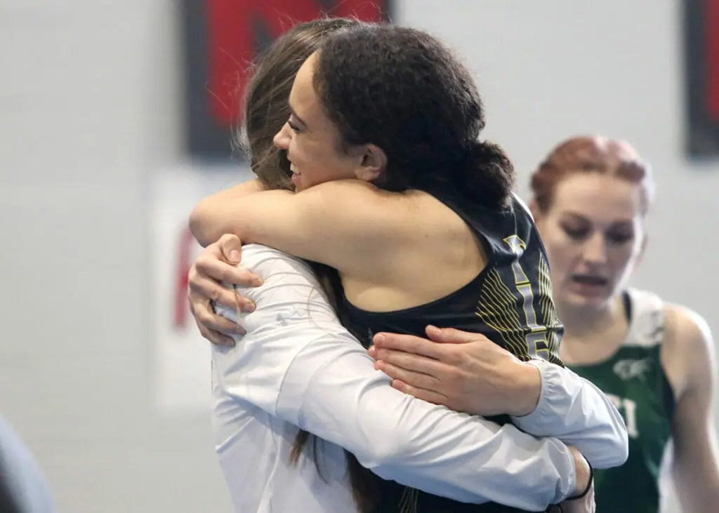 In this image: Maya Reynolds hugs someone after a race.