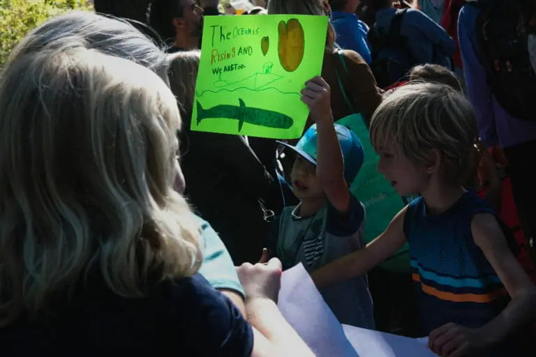In this image: Two children with one of them holding a green sign.