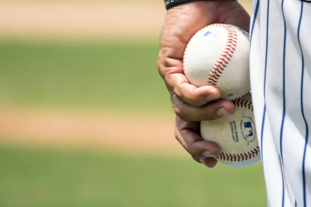 In this image: hand holding baseballs