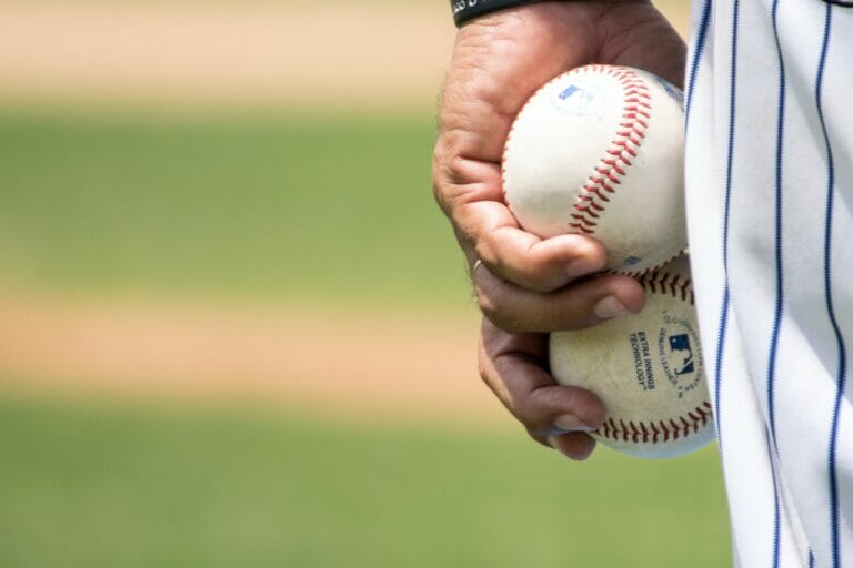 In this image: hand holding baseballs