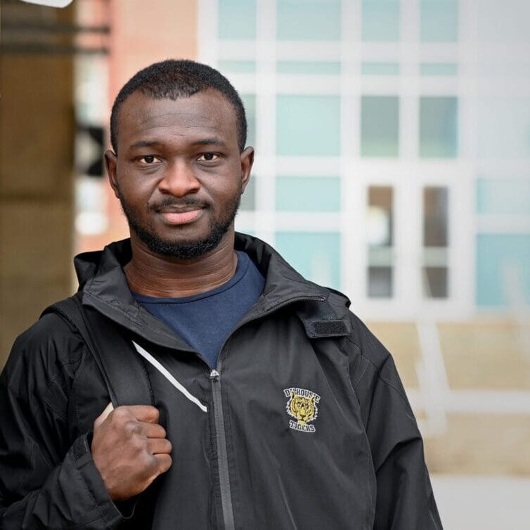 Dalhousie University men’s soccer player Wilfreid Kindo stands with a closed fist while wearing his Dal merch. Photo by Danny Abriel.