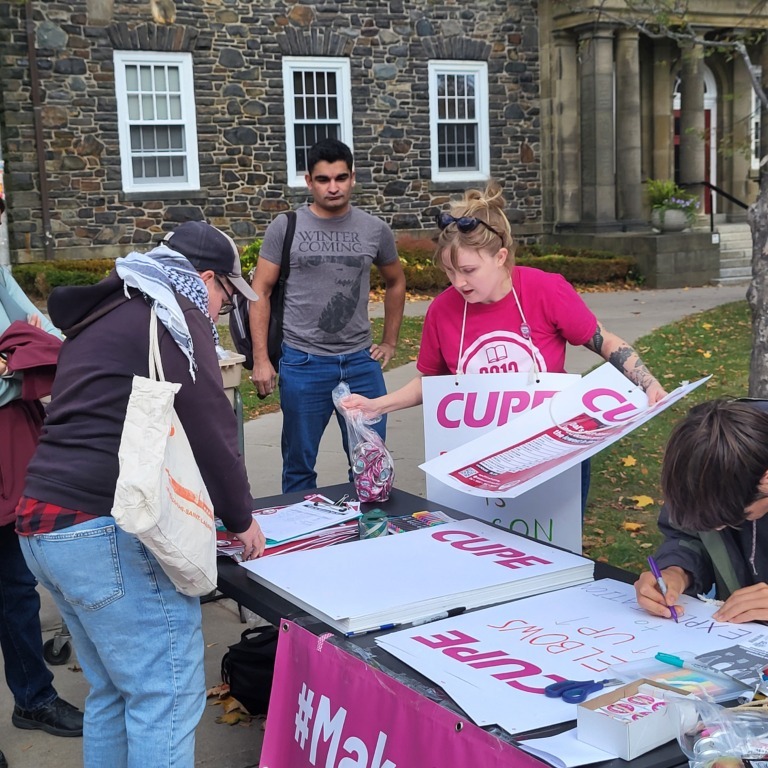 CUPE 3912 members and supporters write signs at a rally on Dalhousie University campus on Friday, Oct. 17, 2025 (Dylan Follett)