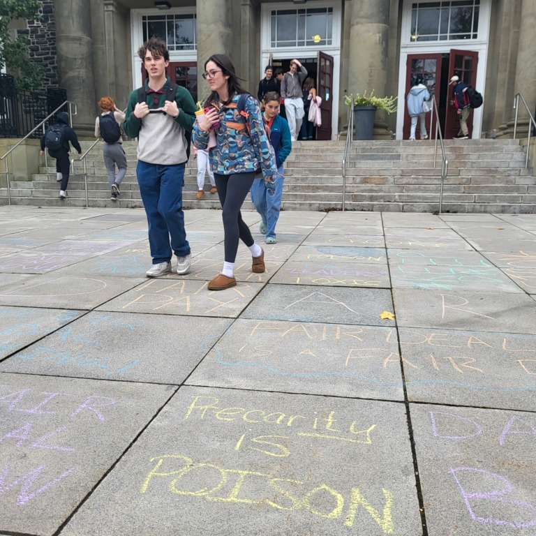 Dalhousie students walk over chalk messages in support of CUPE 3912 outside the Henry Hicks Building after a protest on on Friday, Oct. 17, 2025 (Dylan Follett)