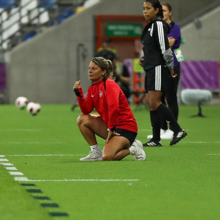 Cindy Tye kneeling on the sidelines during the 2026 women’s soccer U20 World Cup in Poland. Tye coached Team Canada to the quarterfinals, the team's farthest advancement in the tournament since 2014. (Submitted: John Bruce/CSA Media)

