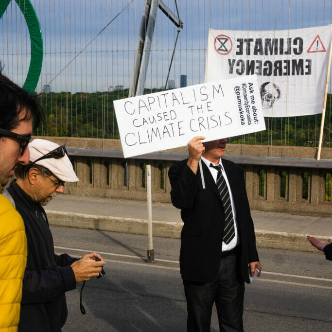 Jeff Mole holds a sign while blocking the Bloor Viaduct bridge in Toronto, Ontario on Monday October 7, 2019.  Mole is promoting alternative economic model’s that would aid in fixing  the climate crisis.