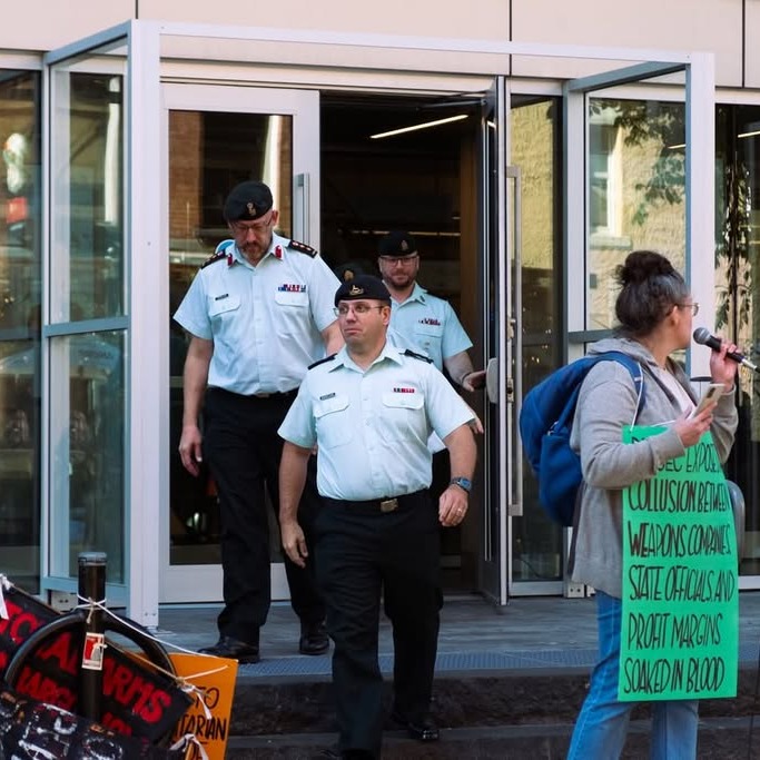 Military members walk past protesters outside DEFSEC Atlantic, a defence and security conference, at the Halifax Convention Centre in Halifax, on Oct. 6. (Photo courtesy of Georgia Gilmore)