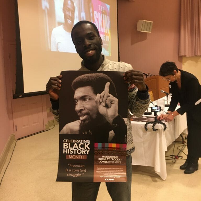 In this image: Desmond Cole holds a Black History Month poster.
