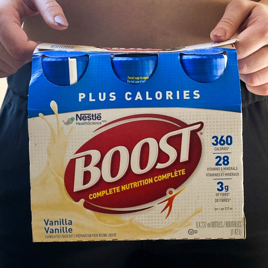 In this image: A person holds a package of Boost.