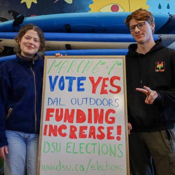 Megan Cooper (L) and Tristan Seely (R) pose in the Dalhousie Outdoors Society gear library in Halifax, Nova Scotia, on Monday, March 3, 2025 (Image by Jenna Olsen) 