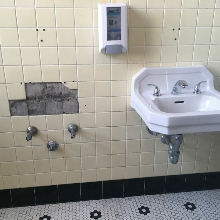 In this image: A women's washroom where one sink is displaced.