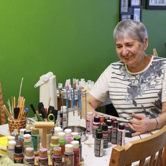 In this image: Dorothea McCorriston in front of her paint supplies.