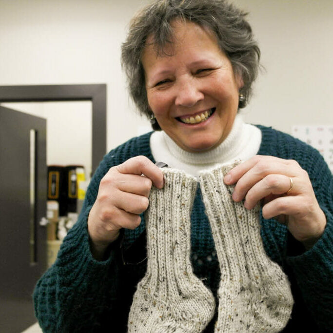 In this image: Irene Swain holds a pair of knitted socks.
