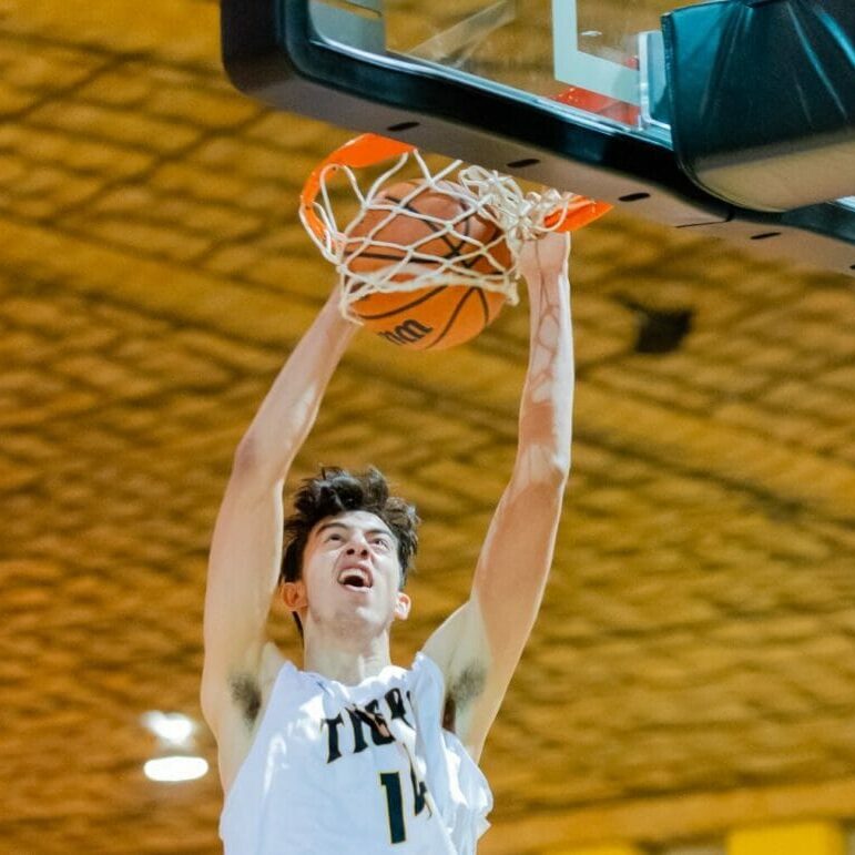 In this image: Sascha Kappos goes to dunk the basketball in a game.