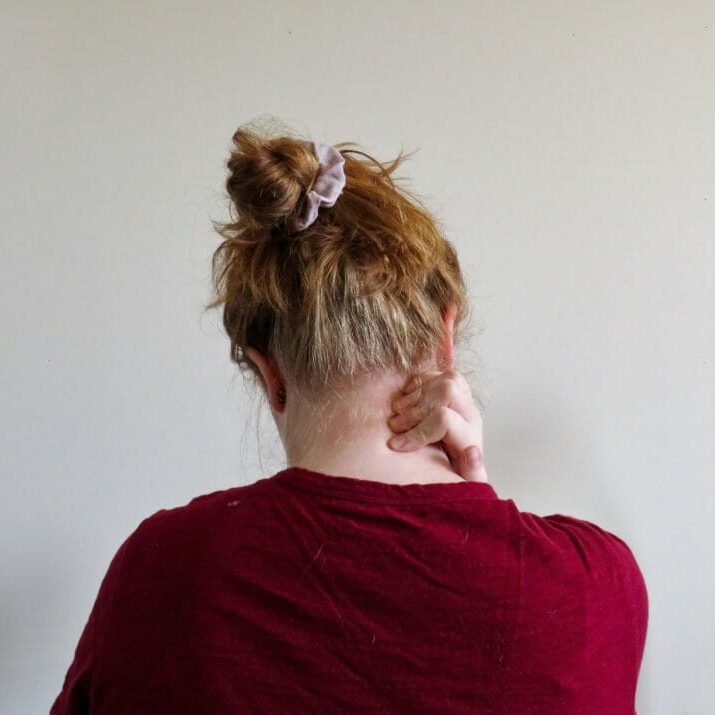 In this image: back of woman rubbing her neck
