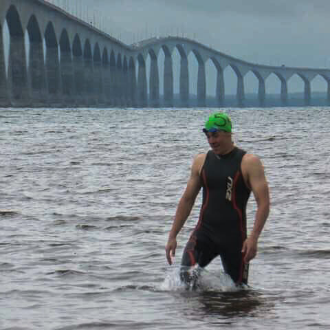 In this image: Tyler Immel-Herron in the shallow part of the Northumberland Strait with the Confederation Bridge in the background.