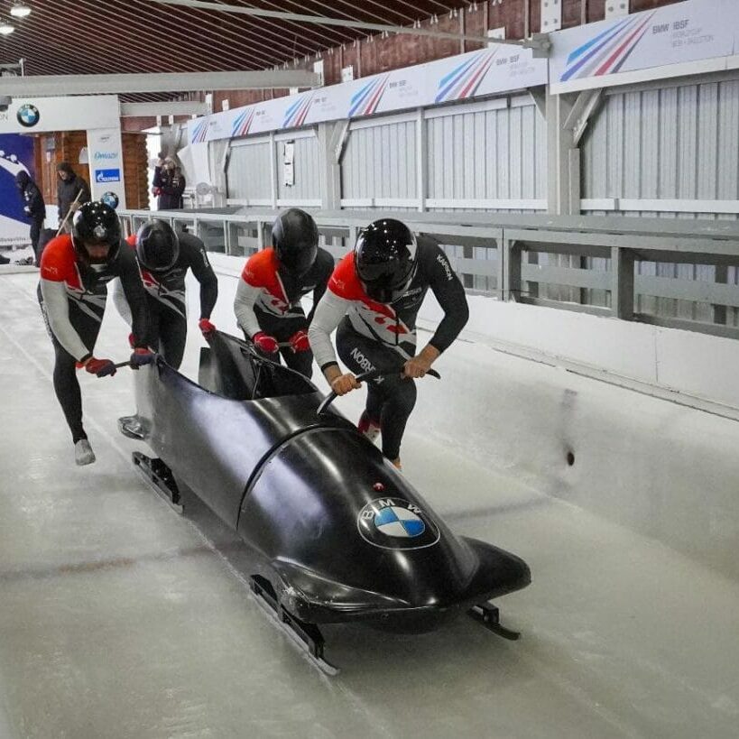 In this image: A bobsled teams pushes off at the start of a track.
